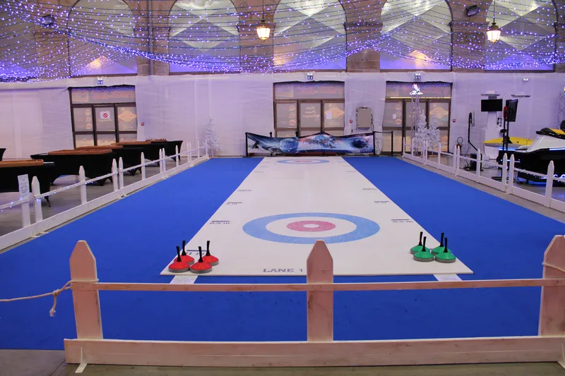 Piste de curling synthétique avec pierres et joueurs en action