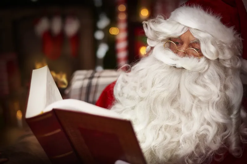 Père Noël en costume traditionnel qui salue les enfants dans une galerie marchande
